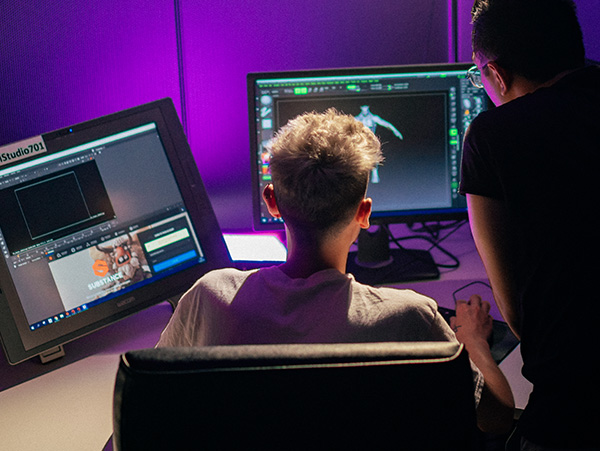 A pair of students working on games design on a computer.