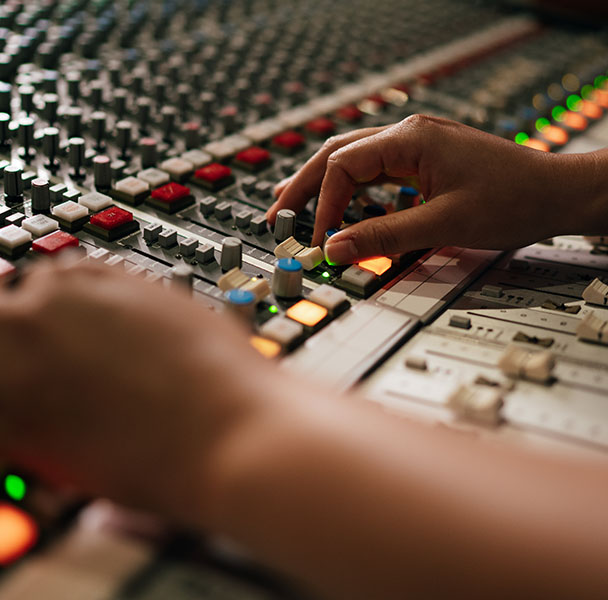 A pair of hands working an audio desk.